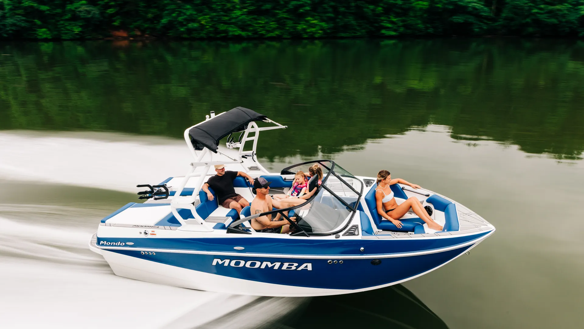A blue and white moomba wake boat driving through the water.