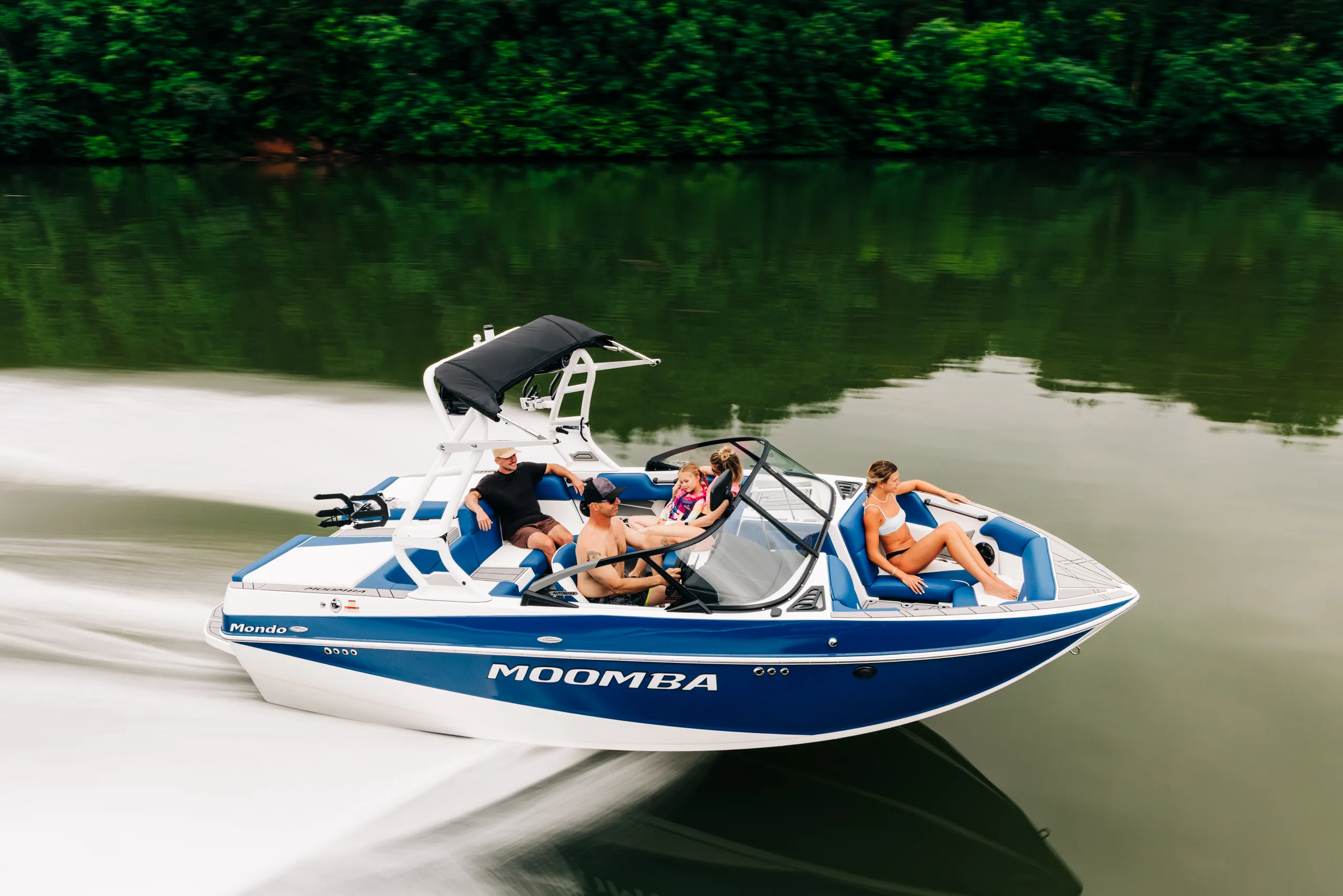 A blue and white moomba wake boat driving through the water.