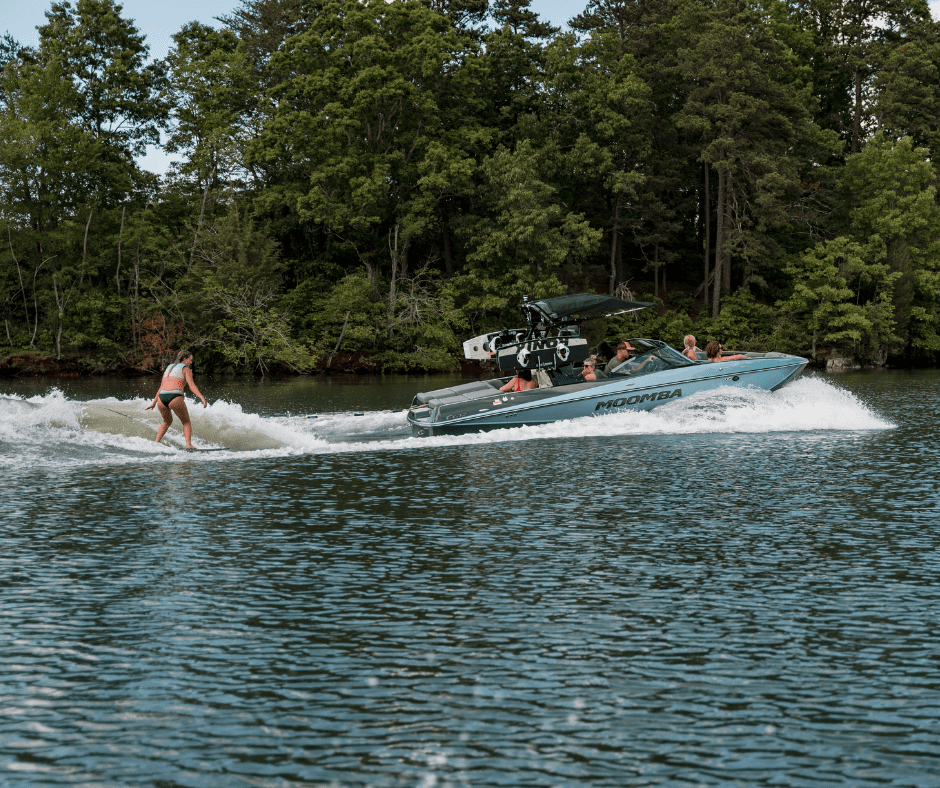 A teenager wake surfs behind a wake boat.