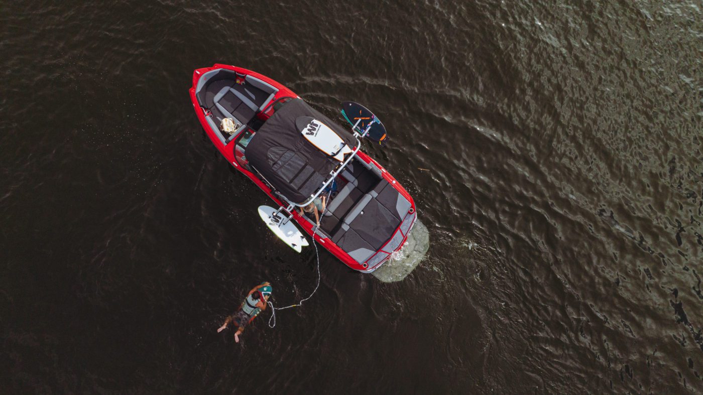 A NXT23 MasterCraft boat in the water with surfers.