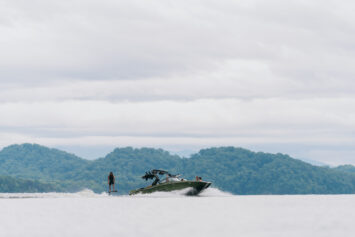 A new 2025 MasterCraft XT24 in the lake with a wakesurfer behind.
