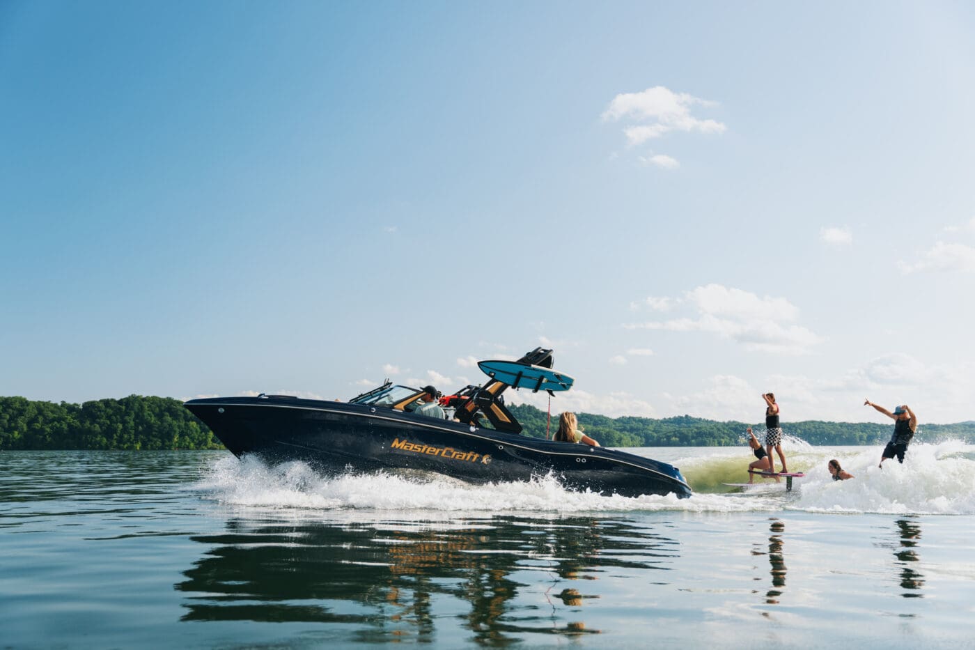 A group of friends wake foiling and wakesuring behind MasterCraft boats