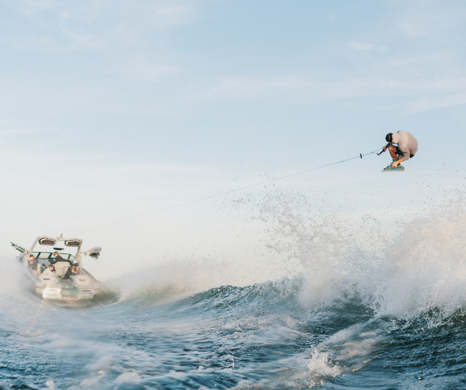 A wakeboarder doing a trick behind a MasterCraft Xstar 25