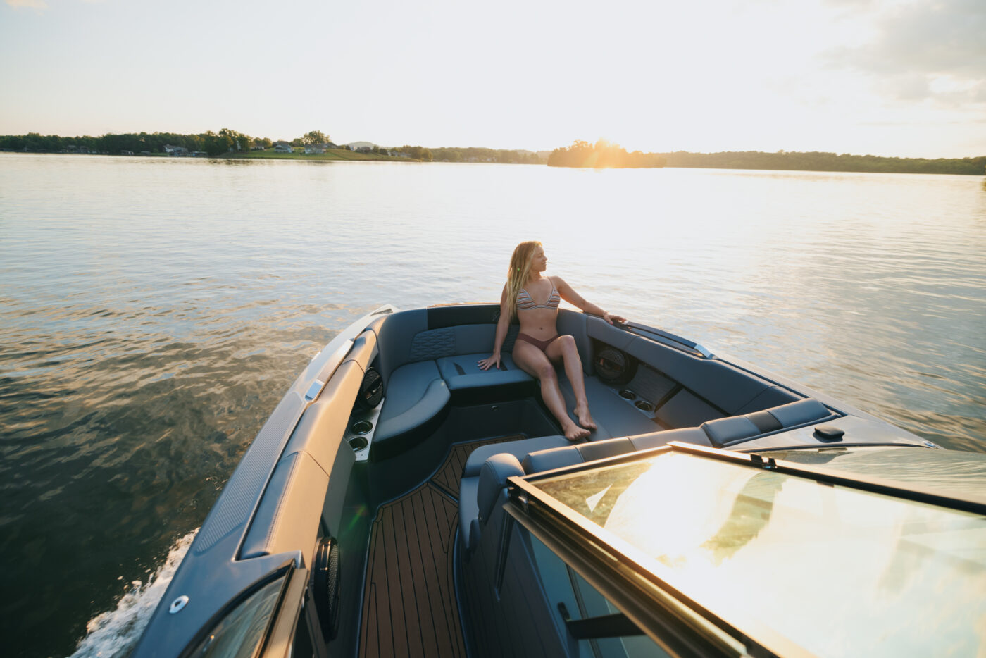 A woman sitting on the bow of a MasterCraft wake boat.