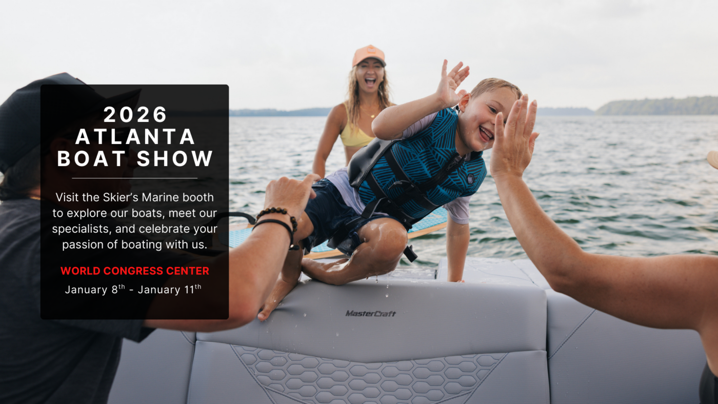 A young boy gets out of the water and high fives a family member on a MasterCraft.