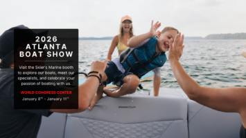 A young boy gets out of the water and high fives a family member on a MasterCraft.